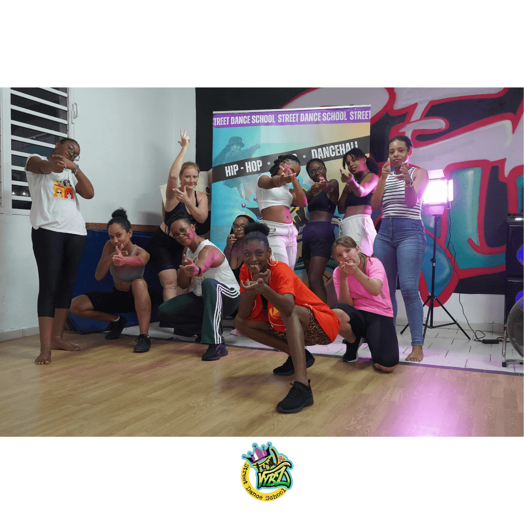 Groupe de danseuses urbaines posant dans un studio devant un mur de graffitis colorés.