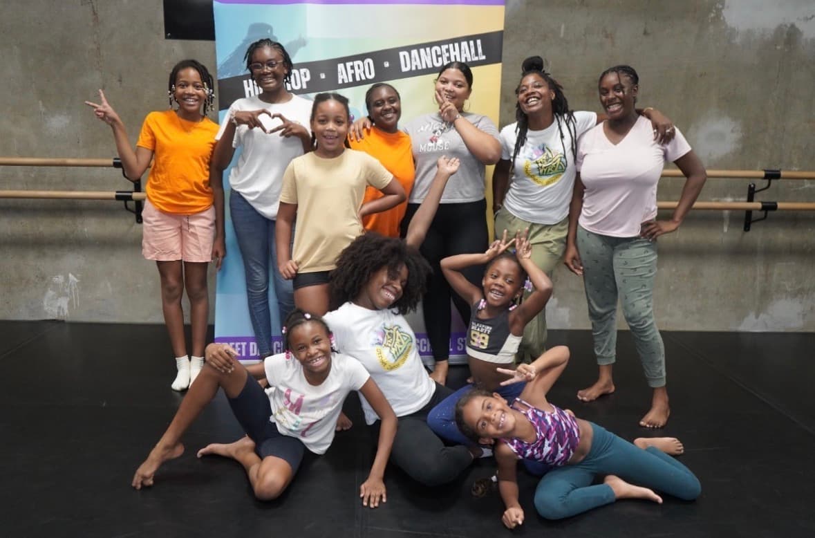 Groupe de jeunes filles et femmes souriantes posant dans un studio de danse urbaine.